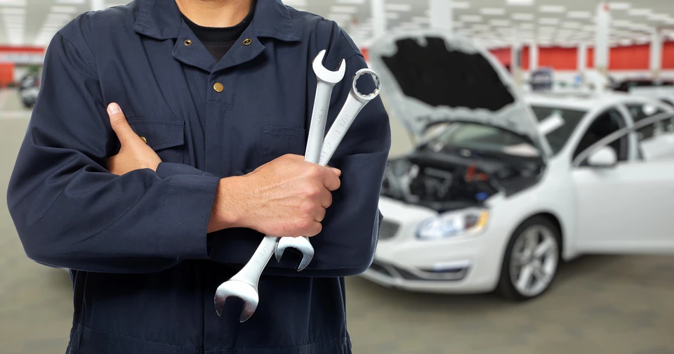 Mécanicien automobile travaillant sous le capot d'un véhicule dans un garage professionnel